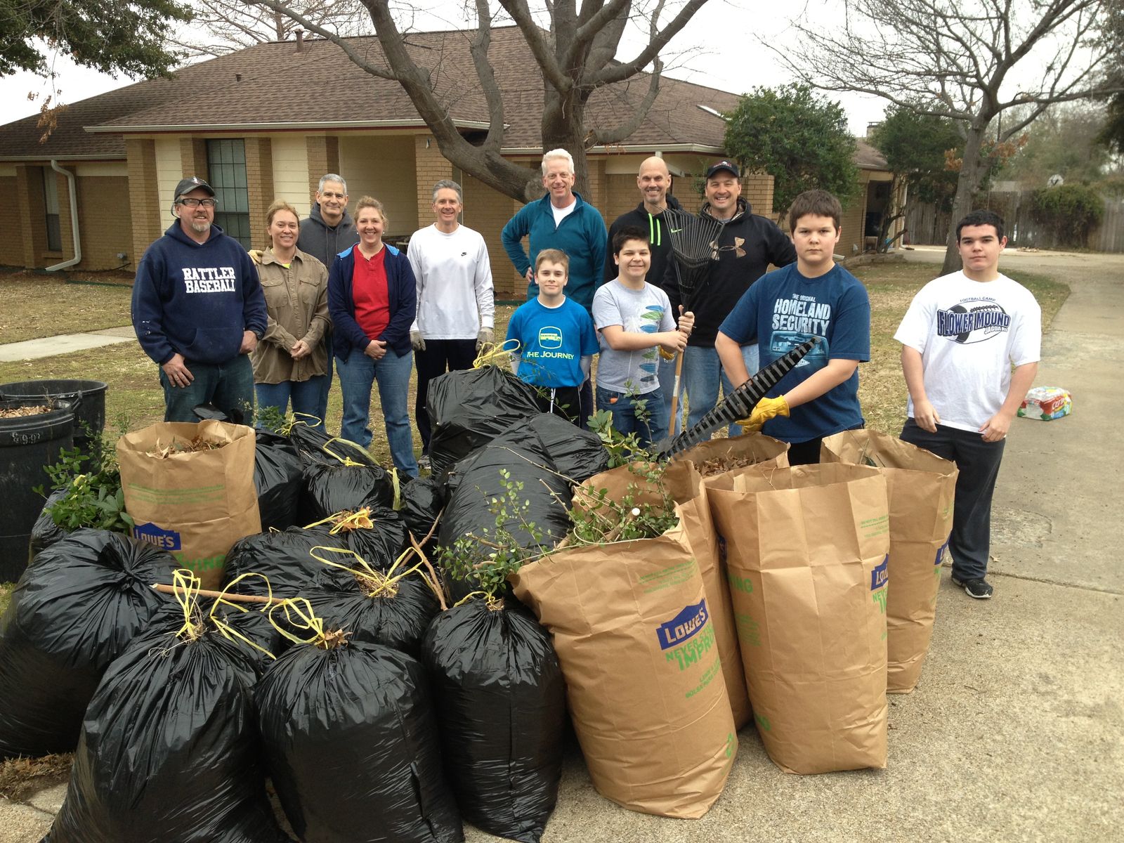 Volunteers standing behind rows of full yard-waste bags after a cleanup